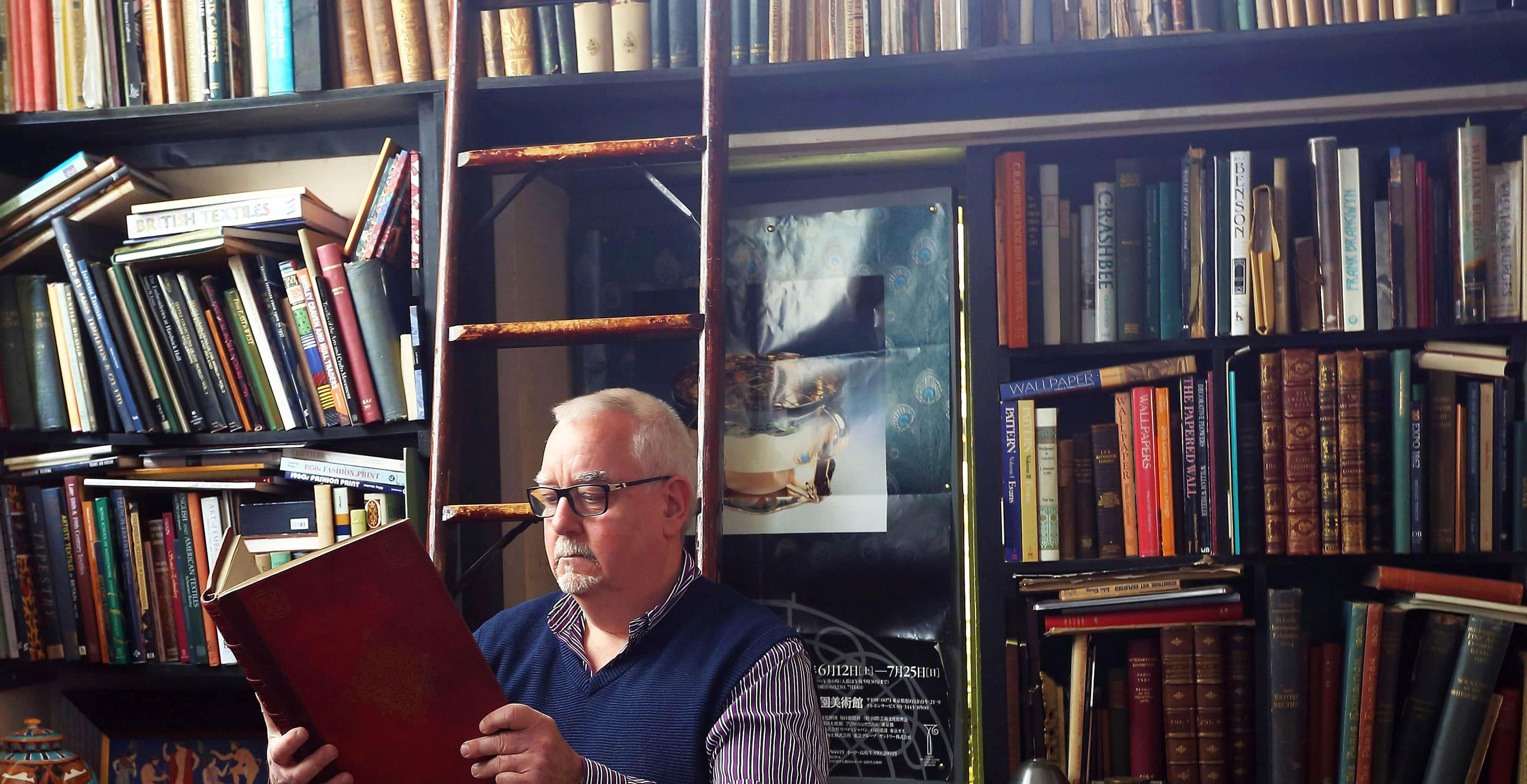 Paul Reeves in his library reading a book