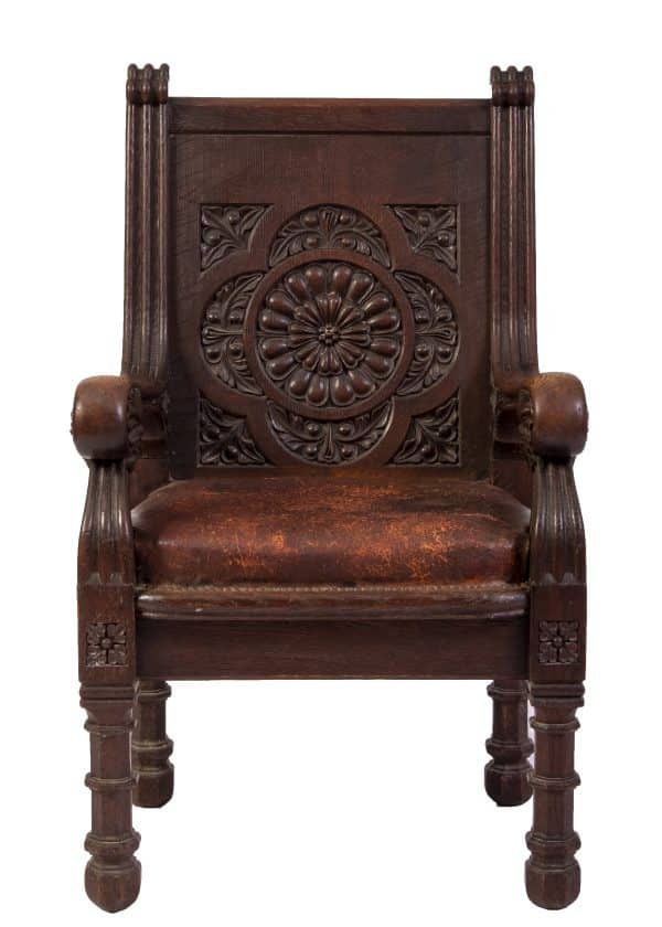  A carved oak chair with a carving in the back support and leather seat 