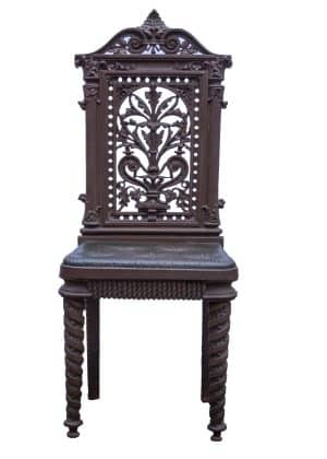 A Jacobean style cast iron hall chair with a trompe l’oeil buttoned cushion.